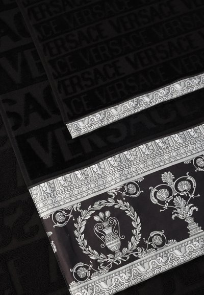 Μαύρες πετσέτες με ανάγλυφο κείμενο "VERSACE" και διακοσμητικό μαύρο και λευκό περίγραμμα με περίτεχνα μοτίβα λουλουδιών και αγγείων.