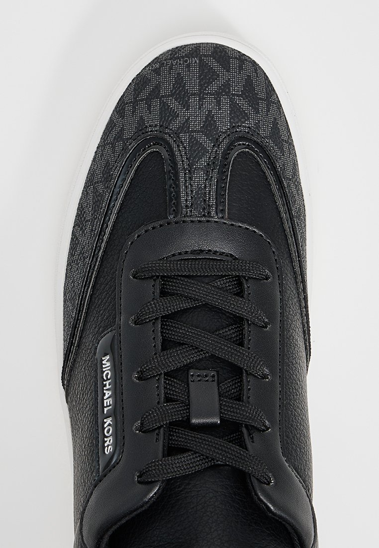 Baskets noires avec une tige en textile à motif et des accents en cuir. Équipées d'un laçage et d'une semelle en caoutchouc blanche. Logo affiché sur le côté.