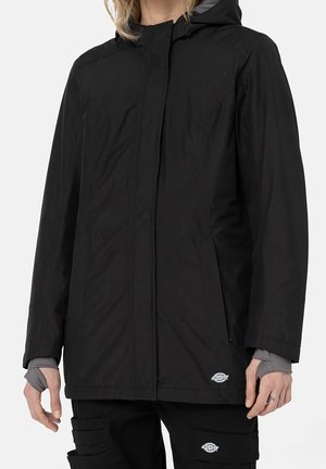 Zwarte waterdichte jas met een capuchon, ritssluiting, zijzakken en een gladde textuur. Bevat een logo op de lagere zoom en elastische manchet.