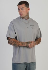 Heledashallane lühikeste varrukatega t-särk, millel on ümar kaelus ja must "SIKSILK" logo rinnal, valmistatud siledast puuvilla segust.