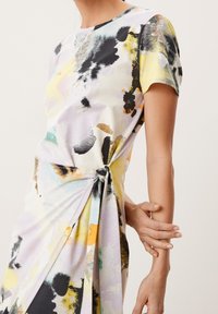 Robe à motif floral en tissu doux, avec des manches courtes, un col rond et un détail de nœud sur le côté pour un intérêt de design supplémentaire.