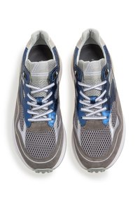 Urheilukengät, joissa on harmaa ja sininen verkkokangas- ja mokkasiinipäällinen, pyöristetty kärki, valkoiset nauhat ja teksturoituja yksityiskohtia.