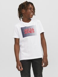 Camiseta blanca de algodón con un gráfico rectangular en azul marino y texto rojo "JACK & JONES", combinada con jeans oscuros. Textura suave, corte relajado.