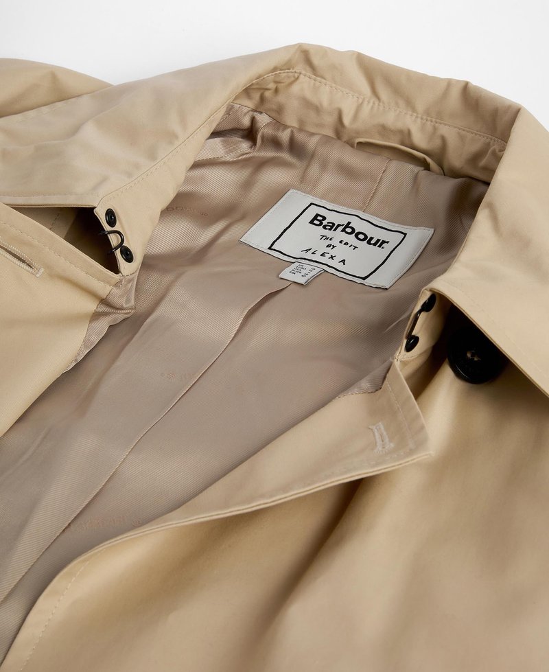 Beige Regenjacke mit glattem Innenfutter. Verfügt über ein Etikett, schwarze Knopfdetails und kontrastierende Nähte entlang der Säume.