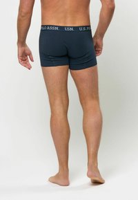 Mørkeblå herrebokser med logoed elastisk linning. Materialet ser glatt ut med en strukturert passform og sømdetaljer.