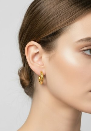 Boucles d'oreilles en or, avec une finition lisse et brillante, structurées en forme circulaire avec une légère torsion et de taille moyenne.