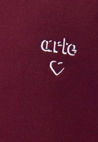 Tessuto bordeaux con testo ricamato bianco "arte" e simbolo di cuore. Texture liscia e design semplice.