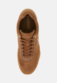 Brązowe zamszowe sneakersy z okrągłym noskiem, tonalnymi sznurówkami i kontrastującymi, teksturowanymi akcentami. Posiadają logo po boku oraz wyściełany kołnierz dla większego komfortu.