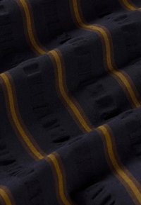 Dunkler Stoff mit abwechselnden orange- und braunen Streifen und einem dezenten strukturierten Muster, das erhabene rechteckige Formen erzeugt.