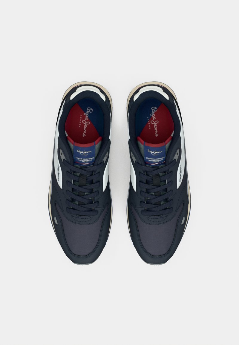 Zapatillas de deporte azul marino con una parte superior de tela texturizada, acentos blancos, cordones negros y una plantilla multicolor con marca.