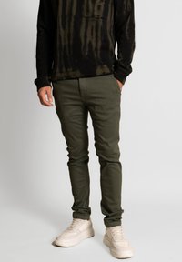 Olivgröna chinos med smal passform i bomullstyg, med en standard fickdesign och som passar bra till krämfärgade sneakers.
