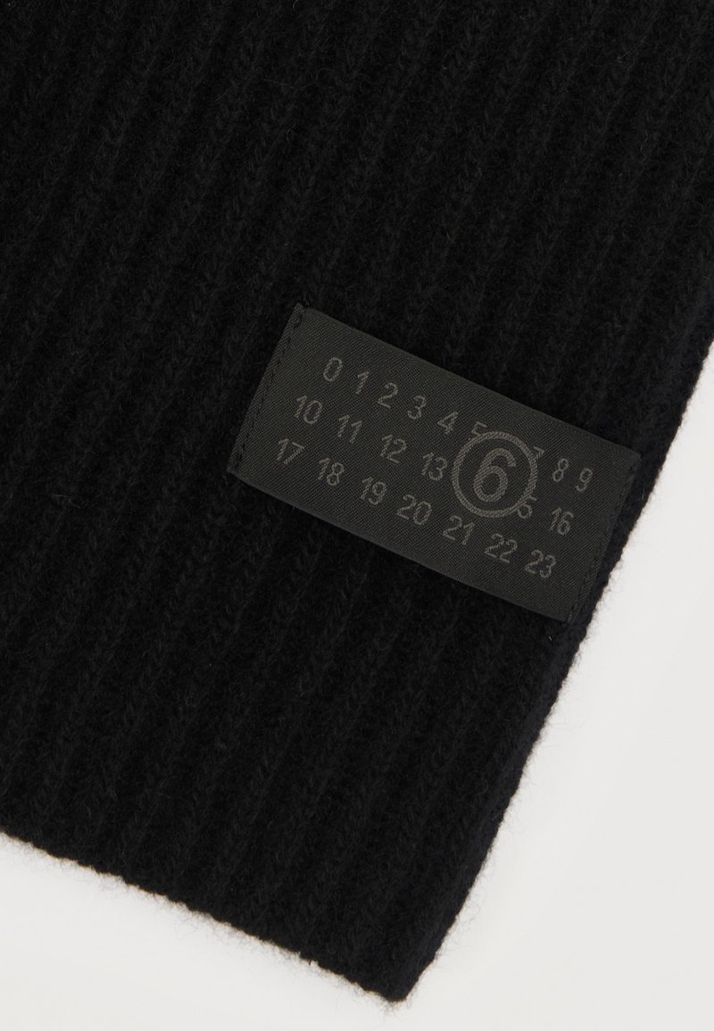 Tissu en laine côtelé noir avec une étiquette rectangulaire cousue affichant les chiffres de 0 à 23, le numéro 6 étant entouré.