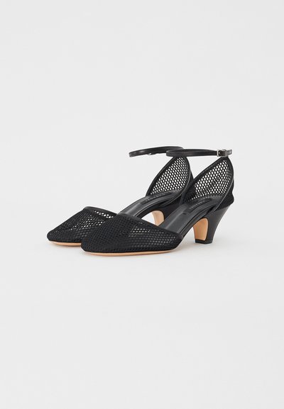 Black mesh heels with a pointed toe, adjustable ankle strap, and a small beige heel, featuring a sleek, textured design.
