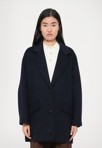 Tumesinise villa- ja polüesteriseguga mantel sälguga kraega, kahe eesmise tasku ja ühe nupuga kinnitusega, millel on lõdvestunud lõige ja pikad varrukad.