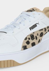 Witte Puma sneaker met beige zool en luipaardprint detail aan de zijkant, witte veters en zwart Puma-logo op het bovenwerk.