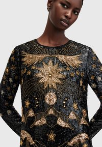 Top negru din paiete, cu modele celestiale din mărgele aurii, inclusiv stele, munți și soare, având un decolteu rotund și mâneci lungi.