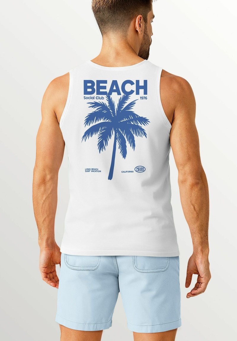 White tank top featuring a blue palm tree graphic with "BEACH Social Club 1976" text. Light blue shorts, visible arm and hand details.