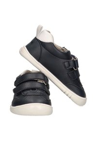 Zapatos de cuero negros con un acento blanco en el talón, que cuentan con dos correas de Velcro ajustables y una suela de goma texturizada.