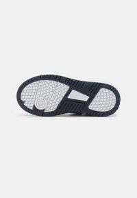 Rubberen sneaker zool met een gestructureerd patroon, voornamelijk marineblauw met witte accenten. Inclusief een rond logo en versterkte randen.
