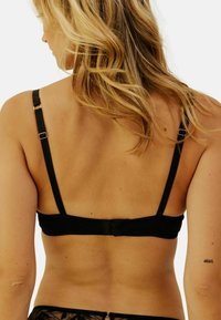 Soutien-gorge noir avec bretelles réglables, fermeture par crochet à l'arrière, doté d'un tissu lisse et d'un design minimaliste.