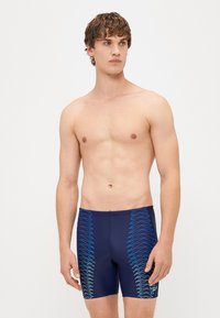 Ναυτικές μαγιό σορτς με μπλε ζιγκ-ζαγκ σχέδιο στα πλάγια, διαθέτουν ελαστική μέση και κομψό σχεδιασμό, κατασκευασμένα από ελαστικό υλικό κολύμβησης.
