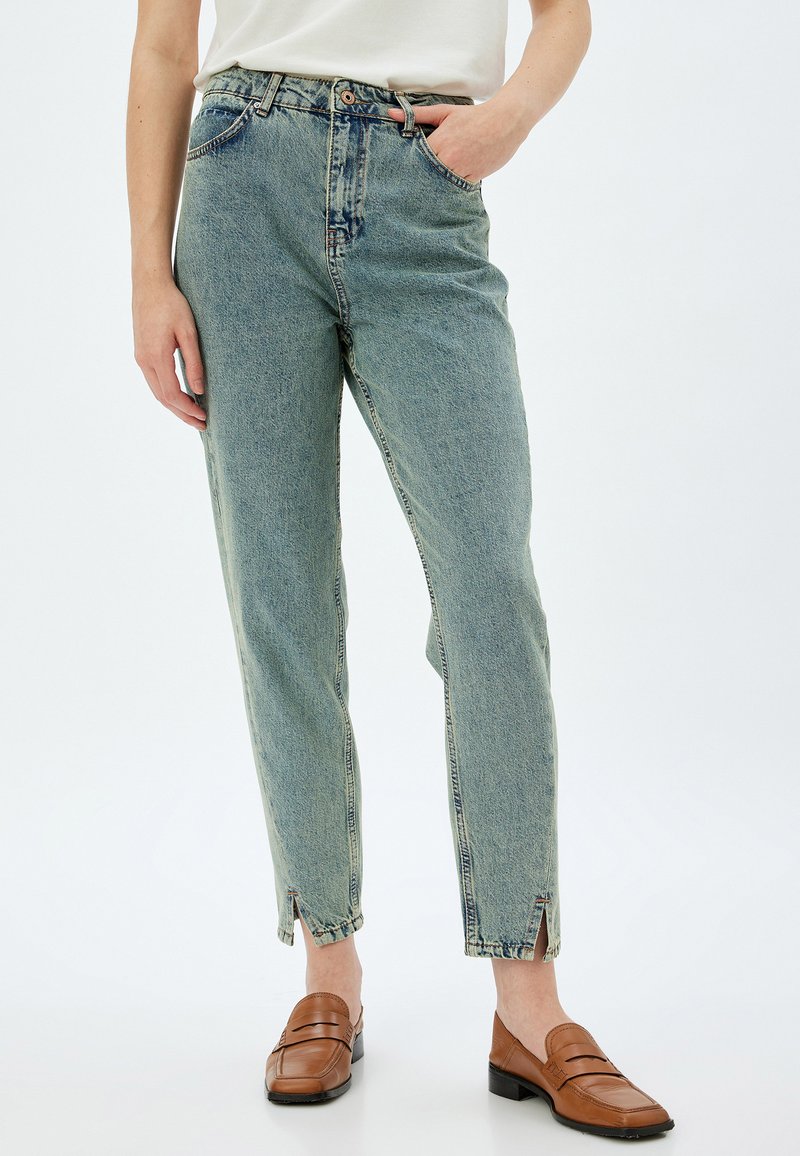 Ljust blå denimjeans med lös passform, hög midja, framfickor och sidsprund vid anklarna. Bärs med bruna loafers.