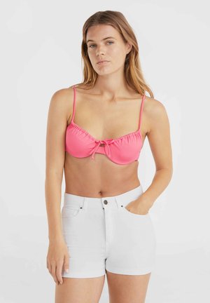 Spīdīgi rozā bikini tops ar ruflemalām un priekšējo mezglu detaļu, saskaņots ar baltām džinsām šortiem ar sānu kabatām un metāla pogu aizdari.