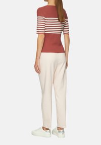 Top de rayas rojas y blancas de manga corta con un diseño ajustado, combinado con pantalones rosa claro y zapatillas blancas con toques plateados.
