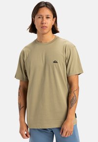 Camiseta de manga corta verde olivo en corte relajado, con un pequeño logo negro en el pecho y textura suave y lisa.