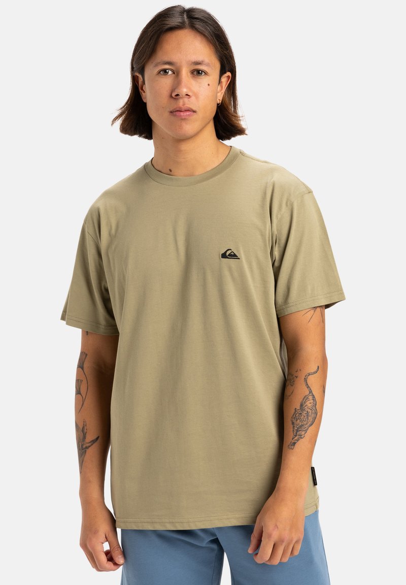 Camiseta de manga corta verde olivo en corte relajado, con un pequeño logo negro en el pecho y textura suave y lisa.