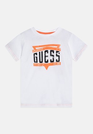 T-shirt blanc à manches courtes avec bordure orange et grand motif "GUESS Los Angeles EST. 1981" orange et noir à l'avant.