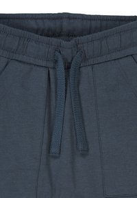 Tmavě modré tepláky s elastickým pasem a šňůrkou, bočními kapsami a měkkou, hladkou texturou.