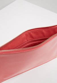 Pouzdro na zip v lesklém růžovém materiálu; hladký povrch s jednou komorou a vnitřní kapsou na zip, zlatý zip.