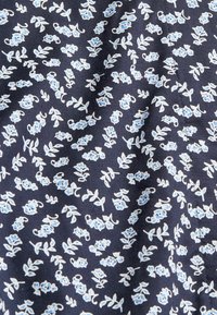Tessuto blu navy con un motivo di piccoli gruppi floreali azzurri e bianchi distribuiti uniformemente sulla superficie.