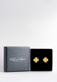 Guldblommiga studörhängen som visas i en svart sammetsklädd låda med en strukturerad mörkblå utsida och vit branding på framsidan.