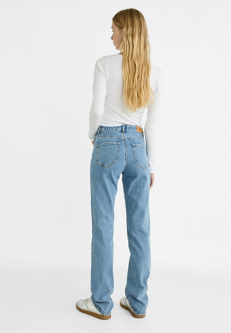 Hellblaue hochgeschnittene Jeans mit geradem Bein, aus Denim gefertigt. Sie verfügen über zwei Gesäßtaschen und ein Lederpatch an der Taille.