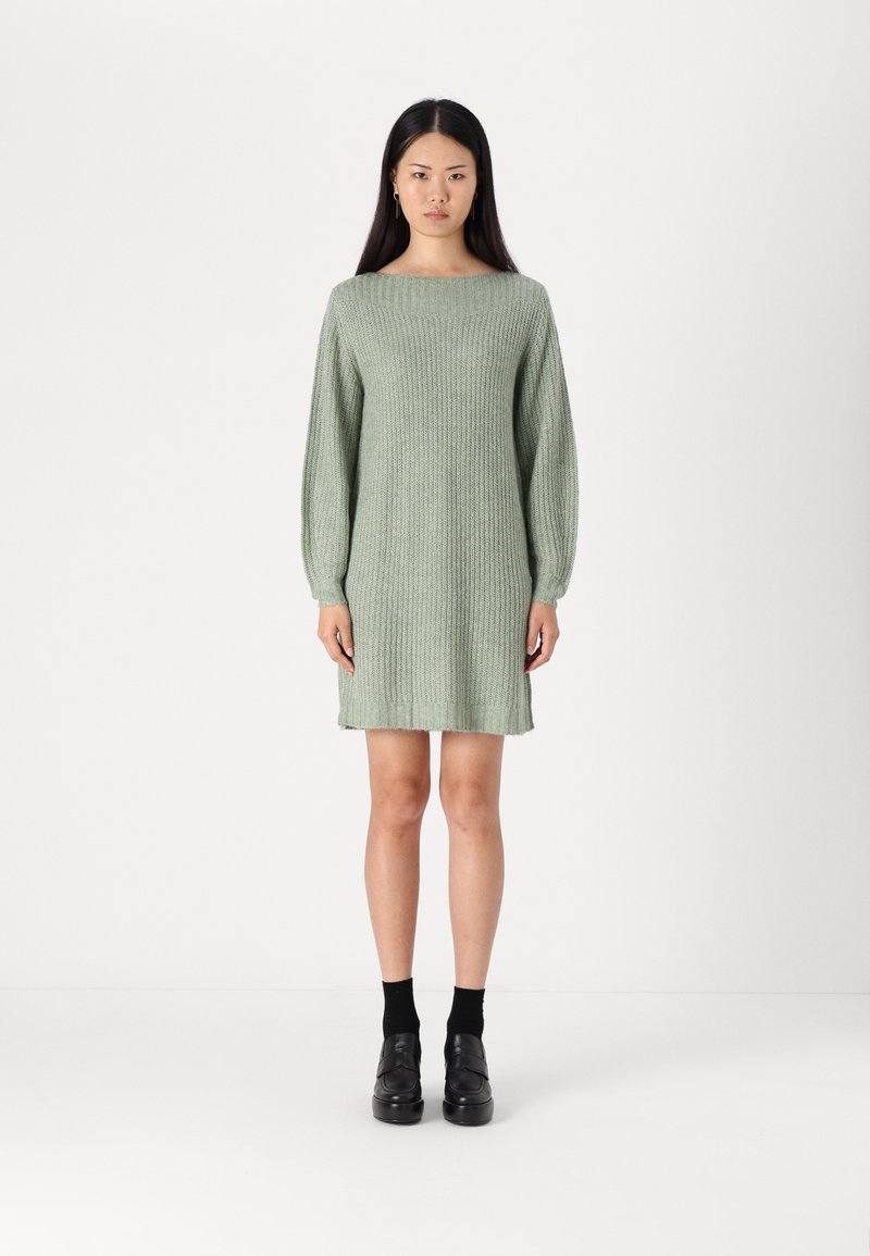 Robe pull tricotée en vert clair avec un col rond, des manches longues et une coupe décontractée. Présente un tissu texturé et un ourlet long jusqu'aux genoux.