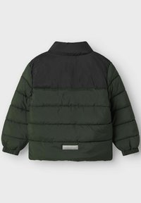 Giubbotto imbottito in verde scuro e nero, con colletto alto, polsini elasticizzati e cuciture orizzontali per l'isolamento. Sul retro è presente una piccola patch con logo.
