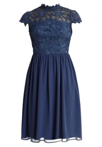 Marinblå klänning med blommig spetsöverdel, genomskinlig övre del av bröstet och ärmar, hög halsringning och draperad kjol som slutar ovanför knäet.
