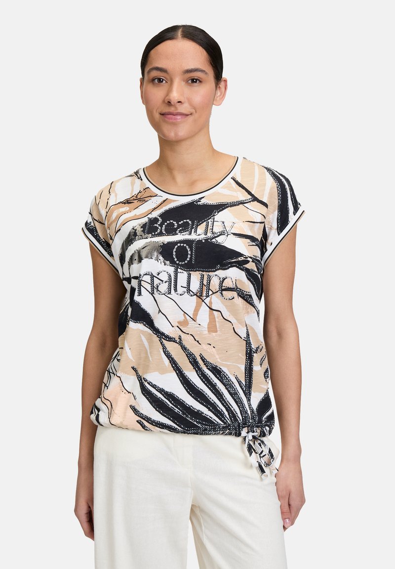 Lightweight, patterned t-shirt featuring a beige, black, and white design with "Beauty of Nature" text, short sleeves, and a tie detail at the hem.