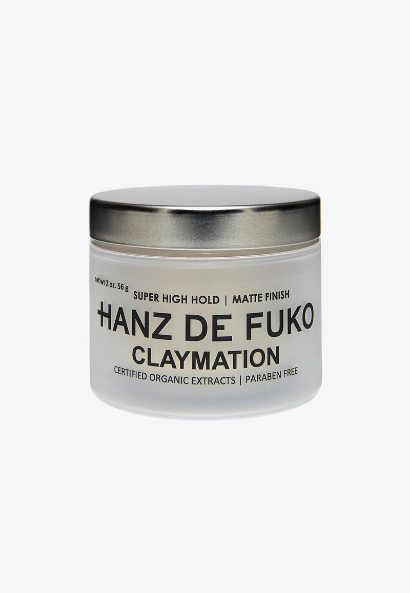 Bevroren glazen pot met een metalen deksel, gelabeld "Hanz de Fuko Claymation," wat wijst op een super sterke hold en matte afwerking. Capaciteit van 2 oz.