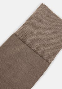 Braune Socke mit einem strukturierten, gerippten oberen Abschnitt und einem glatten Körper, aus einem gestrickten Stoff mit weichem Finish.