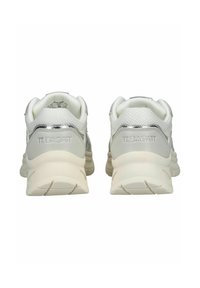 Weiße Sneakers mit einem strukturierten Mesh-Obermaterial, silbernen Akzenten, gepolstertem Absatz und einer beigen Gummisohle. Branding ist an der Ferse sichtbar.
