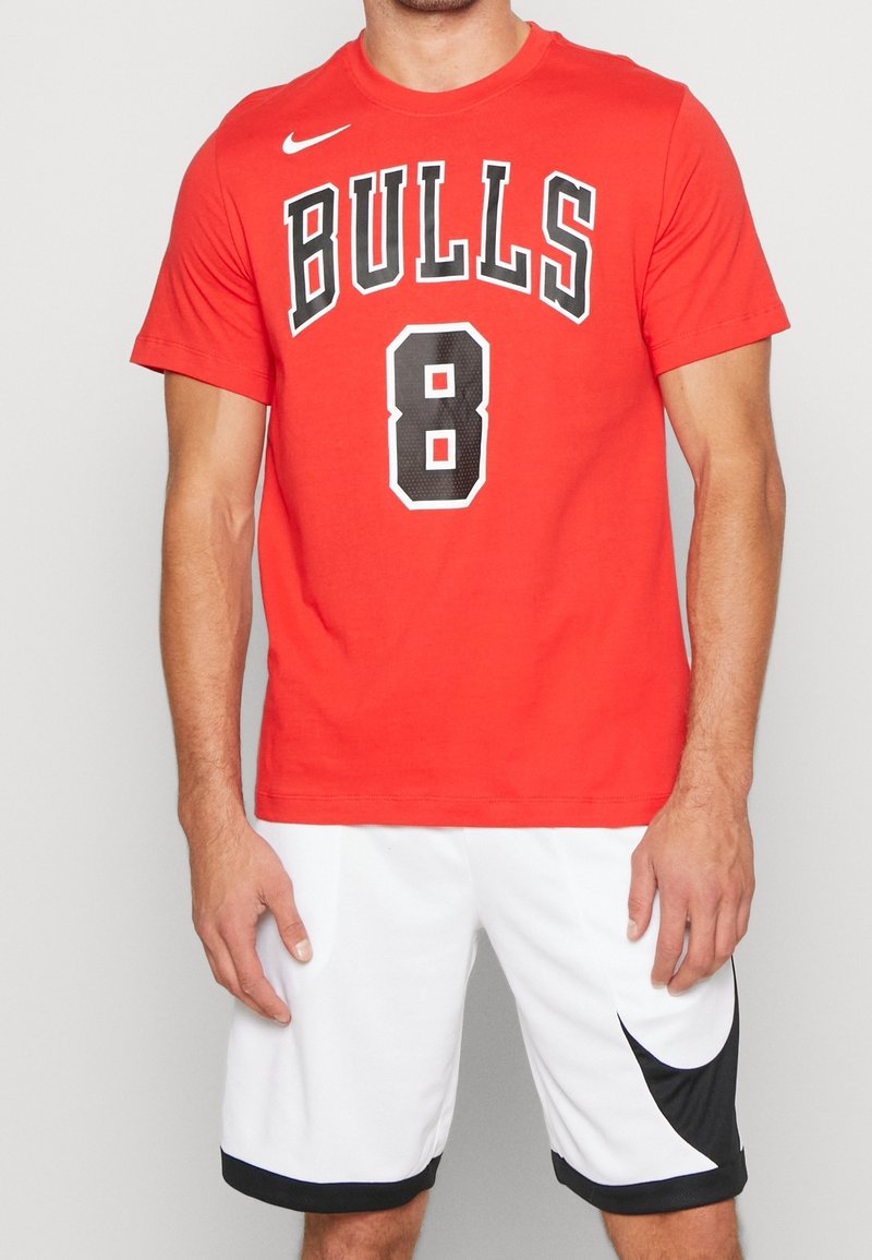 Rotes Baumwoll-T-Shirt mit dem Schriftzug "BULLS" und der Nummer "8" in Schwarz. Dazu weiße Shorts mit einem schwarzen Akzent am Saum.
