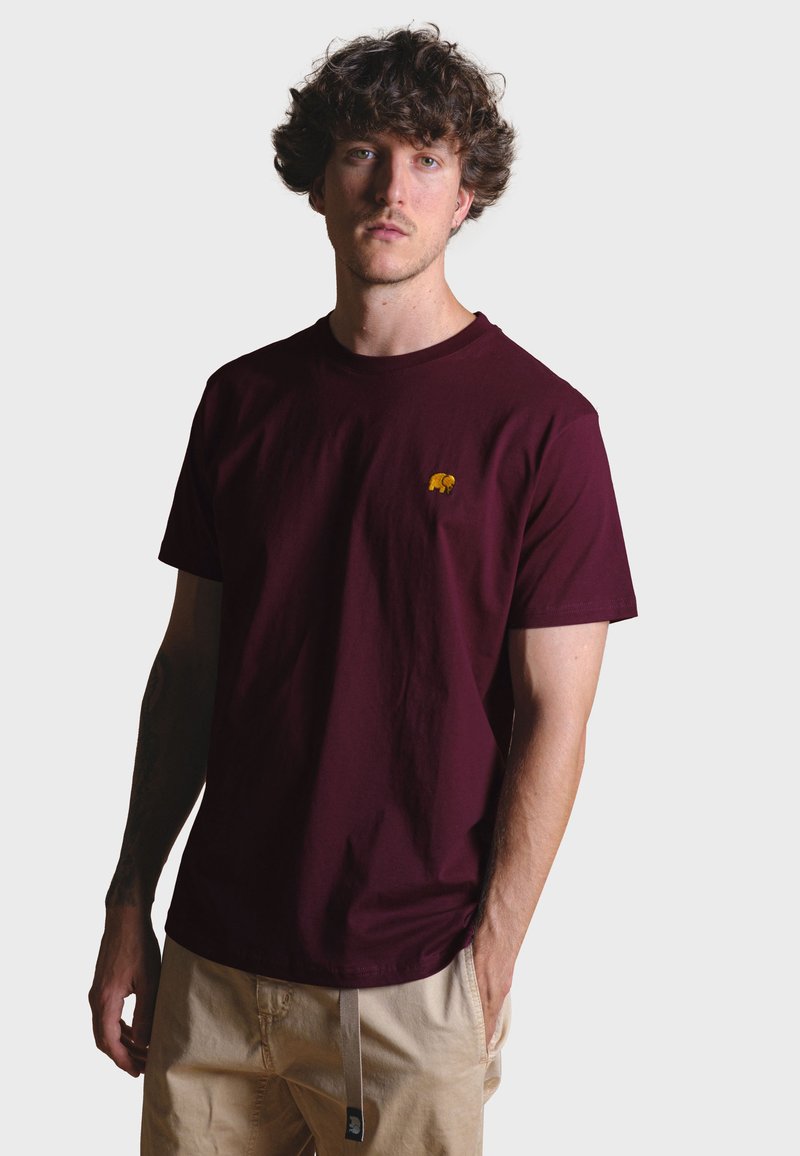 Bordový bavlněný tričko s krátkým rukávem a kulatým výstřihem, se žlutým vyšitým slonem na levé části hrudi.