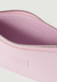 Różowy skórzany piórnik z srebrnym zamkiem, z subtelnym wytłoczonym logo wewnątrz. Gładka faktura, zaokrąglony kształt i minimalistyczny design.