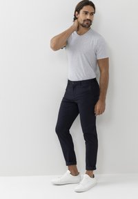 Grå T-shirt med kort ärm, marinblå slim-fit chinos och vita sneakers. Chinos har framfickor och uppvikta ben. Slät tygkänsla.