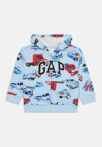 Felpa blu chiaro con un motivo di camion in rosso e nero. Chiusura frontale con zip e grande logo "GAP". Tessuto morbido e polsini elasticizzati.