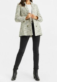 Texturerad ljusgrå kavaj med krage, dubbelknäppning och framfickor. Kombinerad med svarta skinny jeans och ankelstövlar.