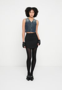 Fekete farmer zipzáras, rövidített mellény, fekete testhez simuló szoknya ívelt szegéllyel, fekete harisnya és hegyes orrú cipő díszes csatokkal. Fekete félkesztyűk.